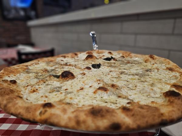 Closeup of a cheese pizza on a red and white checkered tablecloth