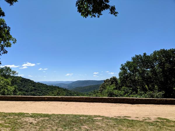 Scenic overlook from Monte Sano Mountain with green wooded hills and distant ridges beneath a bright blue sky.