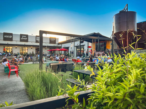 Guests gather across the outdoor courtyard at Stovehouse in Huntsville, enjoying live music, dining, and drinks surrounded by restaurants and colorful seating.
