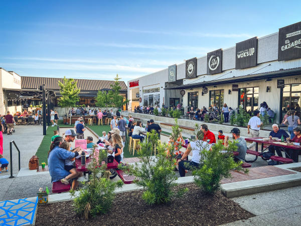 A bunch of people enjoying the weather outside Stovehouse eating and relaxing on the patio area