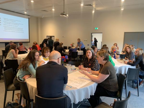 A conference room filled with small tables of people talking.