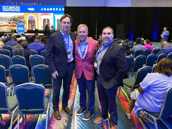 Three men in suit jackets attend a conference