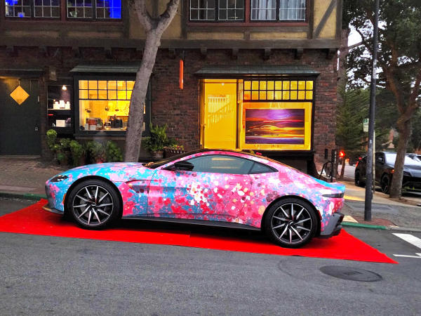 This is an image of an Aston Martin parked outside of Meuse Gallery on Ocean Avenue in Carmel-by-the-Sea