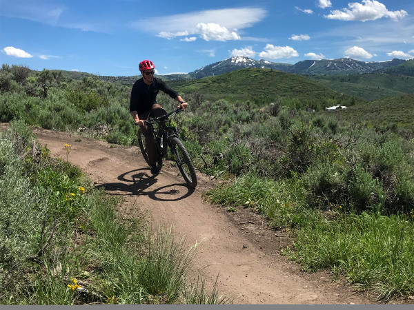 Guy Riding Mountain Bike with Mountains in Background