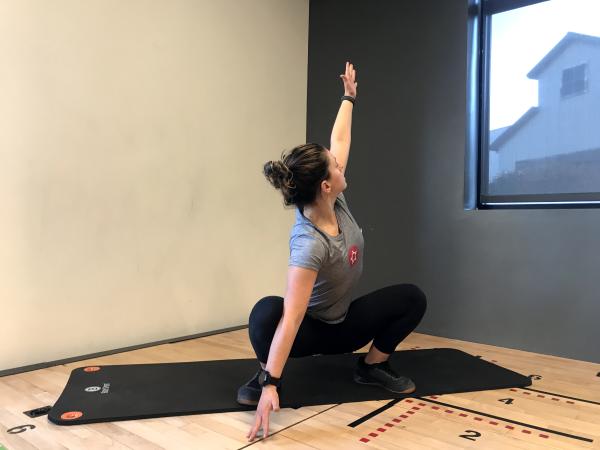 Instructor demonstrating "wide deep squat with a twist" exercise