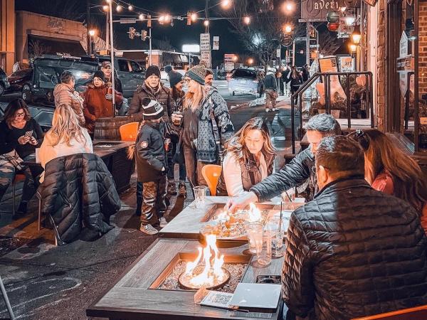 Small groups of people gather around fire pits for dining and fun at Chatty Monks on a winter's night.