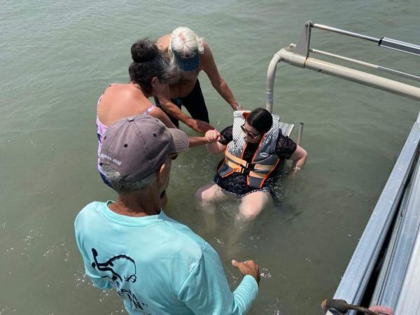 Person with a disability using the automated chair from the ICAN fishing boat to be lowered into the water