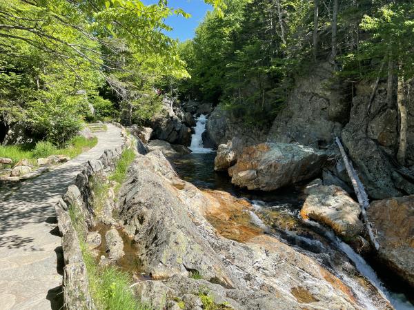 View of Glen Ellis Falls with a stone trail on the bank in Jackson, NH.