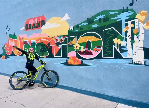 Girl on a bike in front of a "Welcome to Grand Junction" mural in Downtown Grand Junction