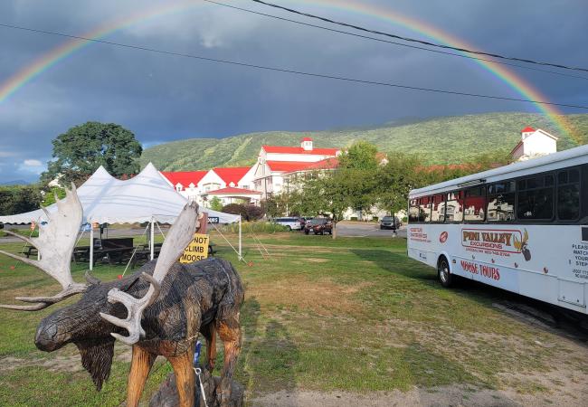 Pemi Valley Moose Tours Bus with Moose Carving in Foreground and Rainbow in Background