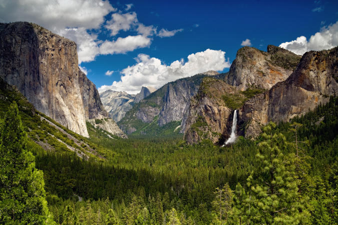landscape of trees, mountains, and waterfalls