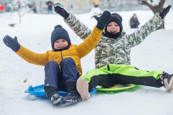 Two Kids Sledding in the Snow
