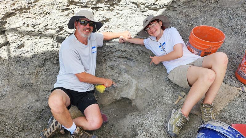 Two people posing with an artifact on a Dino Dig
