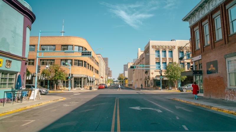 Looking northbound up 5th Street and Central Avenue, with the road flanked by the KiMo Theatre to the right and the Sears Building to the left. There are pedestrians walking up the sidewalk.