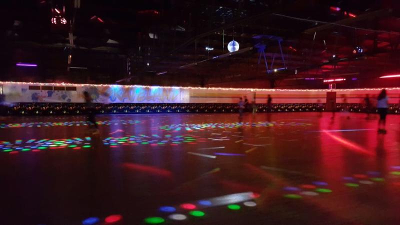 People skating on the disco-lit floor of Western Skateland