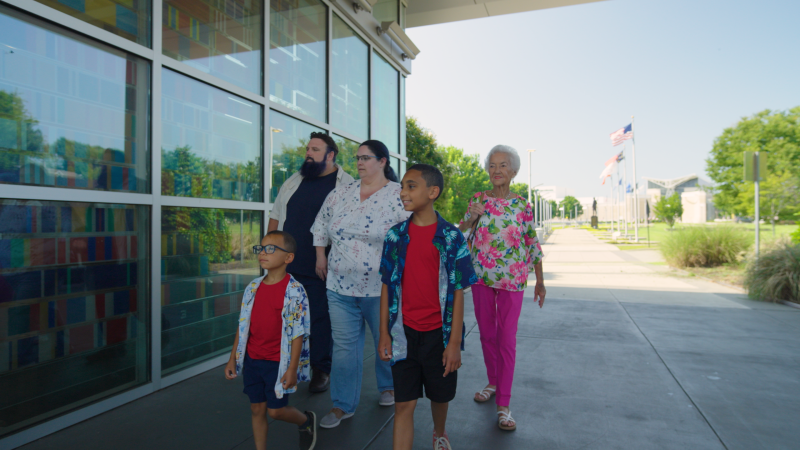 Multi-Generational family visiting Fayetteville's Veterans' Park with the ASOM in the background