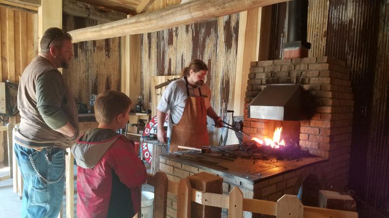 A father and son enjoy the blacksmith demonstration at Waverly Park.