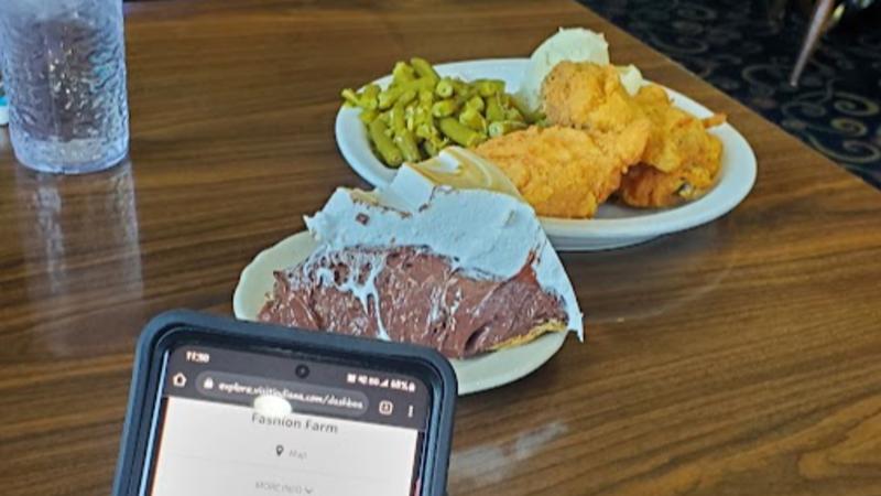 A traditional meal from Gray Brothers Cafeteria in Mooresville sits in the background, as a visitor checks in on the Indiana Culinary Trails Digital Passport.