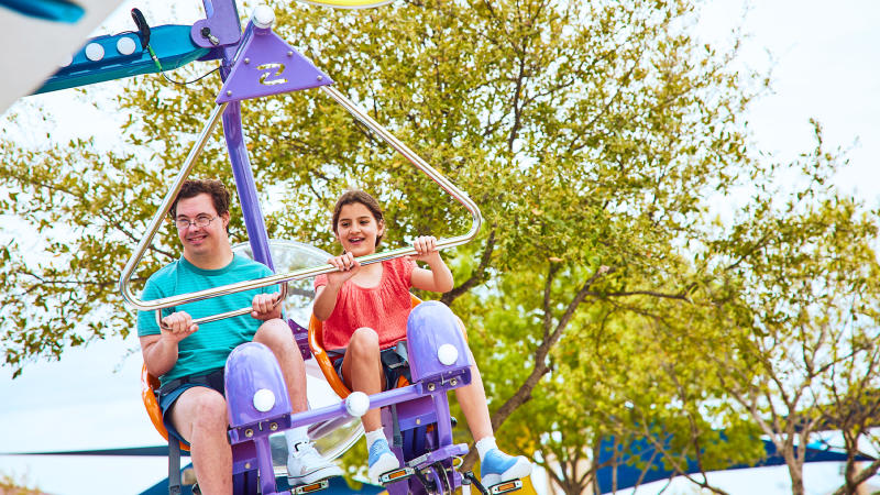 Boy and girl on air ride with trees behind them
