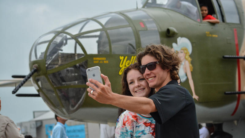 Young couple taking selfie with WWII plane