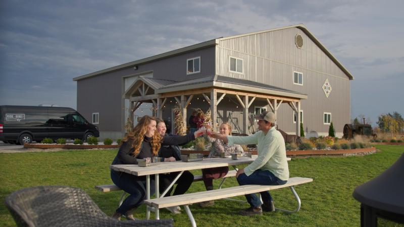 Group doing cheers with cider on picnic bench
