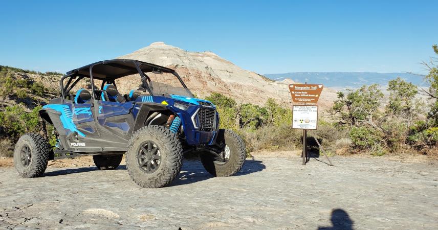 Picture of Blue Jeep in Desert Parked in Front of Sign