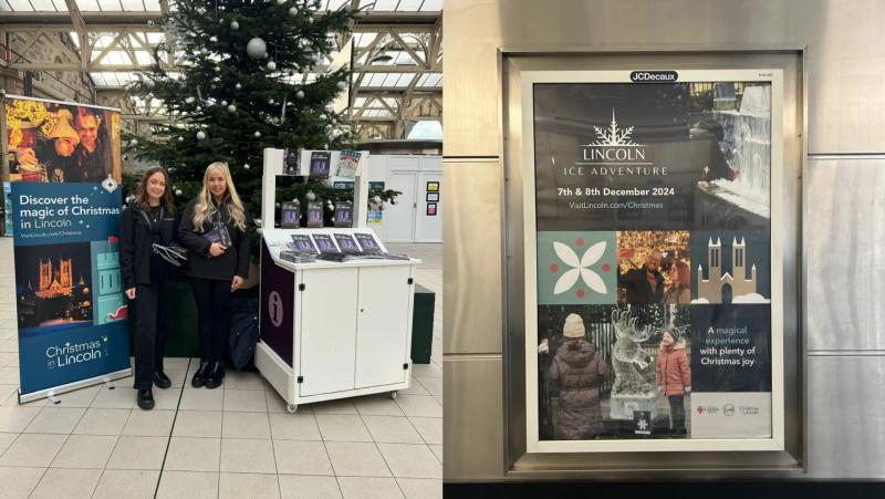 Two women stood posing in front of a Christmas tree ansd stand filled with Christmas guides.