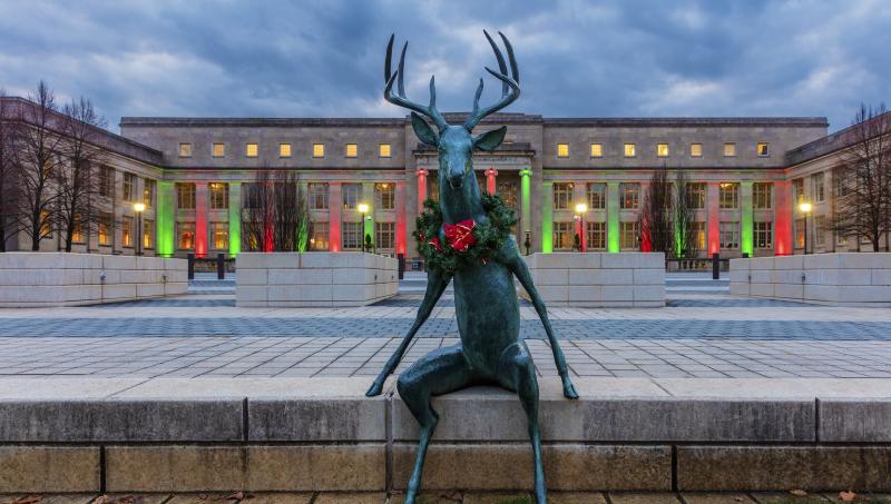 Scioto Mile deer sculpture decked for the holidays with wreath in front of COSI lit with festive holiday lights