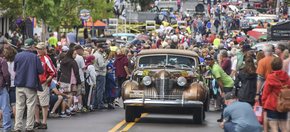 Classic car in a crowd of people at a previous Great Race event.
