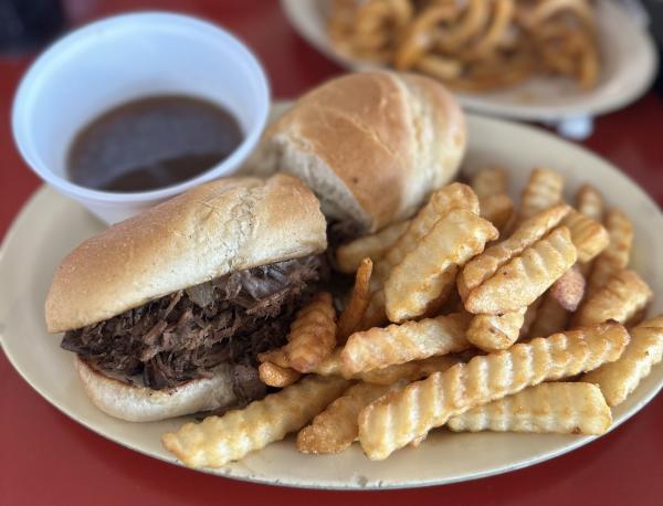 A pulled pork sandwich with a side of crinkle cut fries sit on top of a dish at Ed Walker's, Fort Smith.