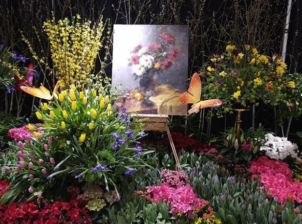 Colorful plants surround a floral painting at the Capital Region Flower and Garden Show