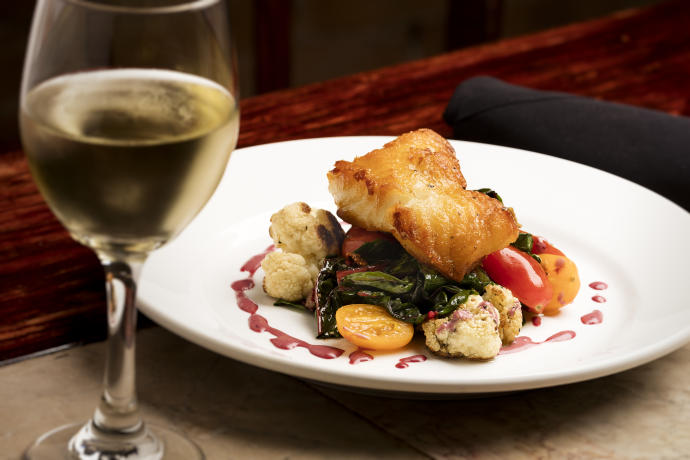 A plated fish and vegetables dinner paired with white wine in at The Bistro in Bowling Green, KY