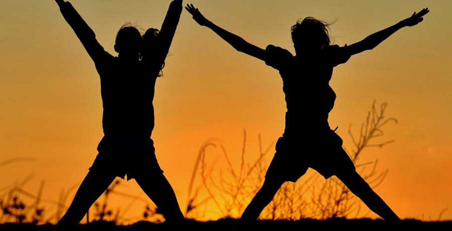 Two people exercising silhouetted against the evening sky