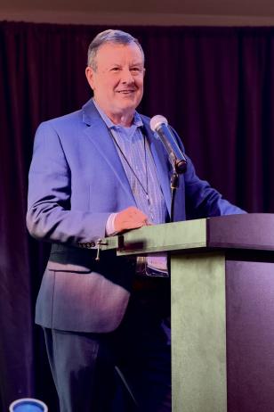 Nick Wolda speaks at a podium during the PASMAA Magisterial Session at Carlton Woods in The Woodlands, TX.