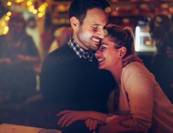 A couple laughs while embracing one another during a night out.