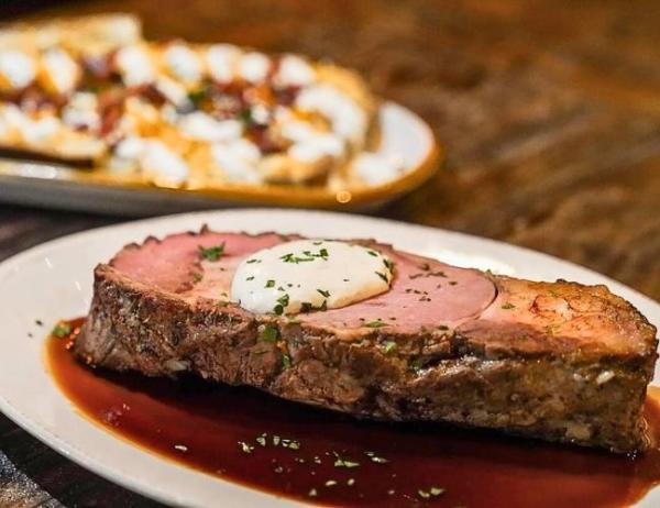 A medium-well steak sits on top of a plate garnished with butter and fresh herbs at StoneHouse, Fort Smith, Arkansas.