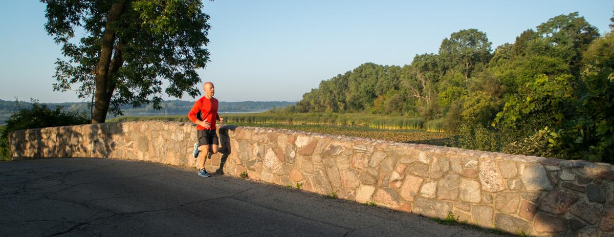 A man runs across a bridge at Lake Wingra in the golden hour.