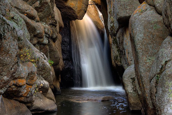 A stunning waterfall nestled between large rock formations at Curt Gowdy State Park, one of the hidden gems near Cheyenne, Wyoming.