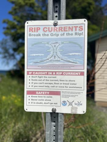 Sign warning about rip currents near Lake Superior shore in Marquette, MI