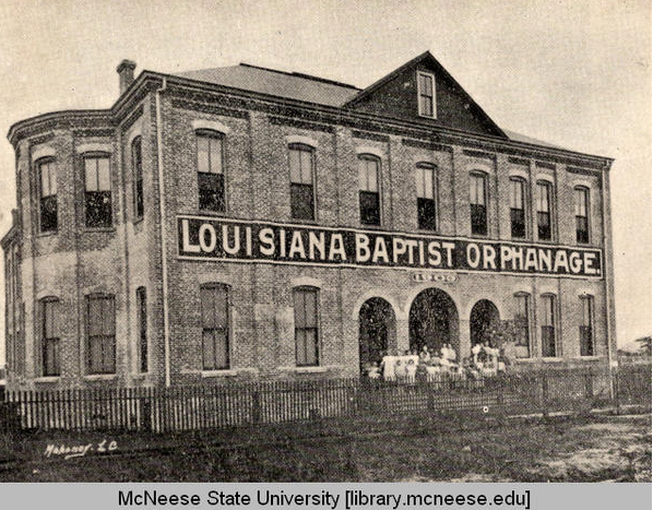 black and whit photo of multi story orphanage with children in front
