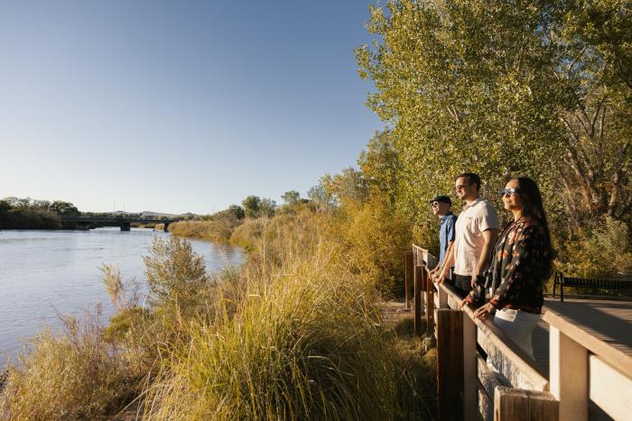Three people look out over the Rio Grande in the bosque.