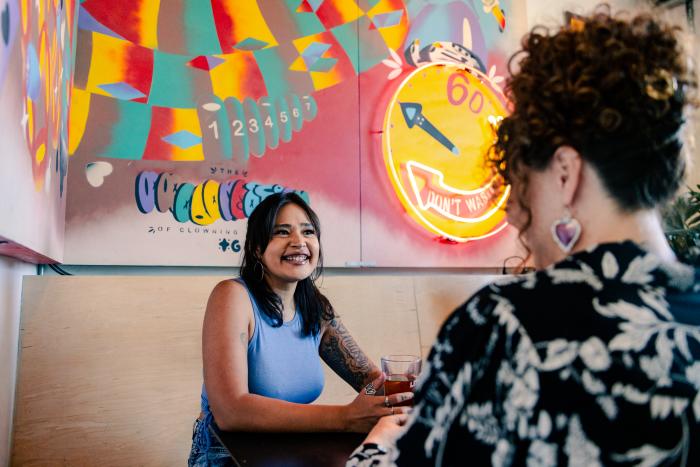 Two women talk at a table in Little Bear Nob Hill