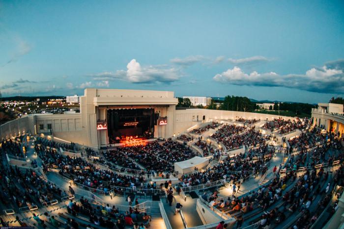 Crowd gathered for a concert at The Orion Amphitheater in Huntsville, with the stage and surrounding seating visible at dusk.