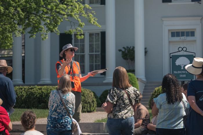 Guide leading a walking tour through Huntsville’s Twickenham Historic District, speaking to a group in front of a historic home.