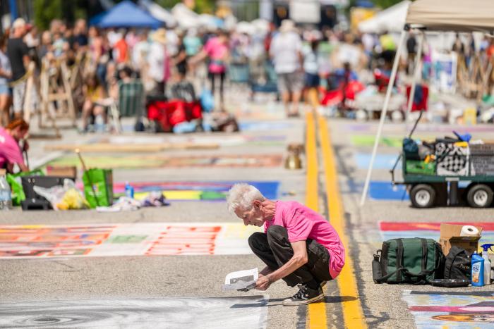 Man illustrates art on street with chalk