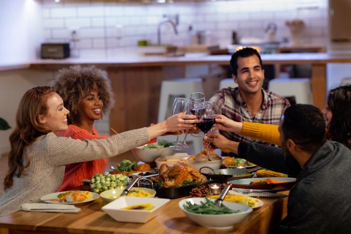 A group of people clink their wine glasses at a Thanksgiving dinner