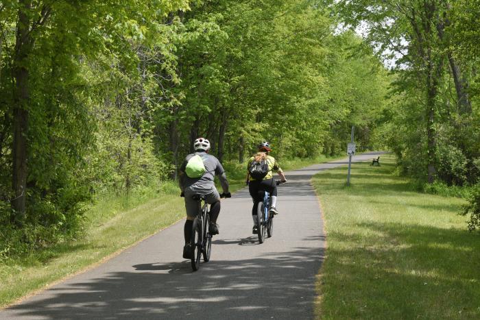 two people riding bikes on a path