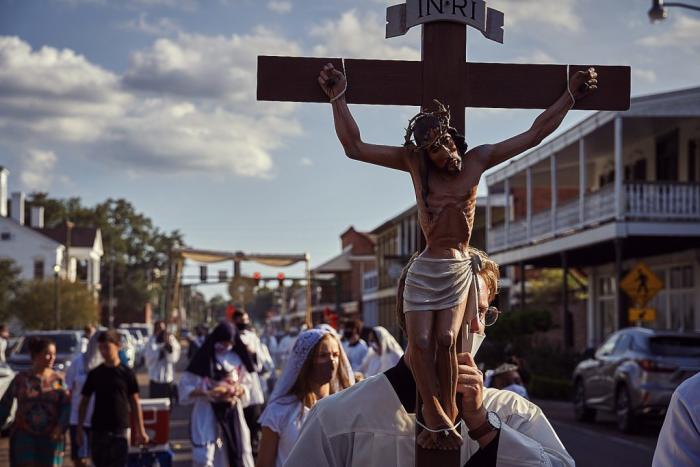 man walking with large crucifix