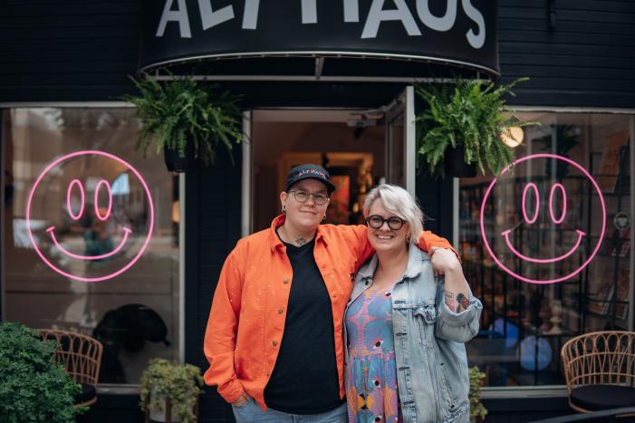 A couple stand close outside their shop.