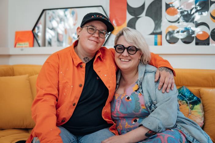 A couple sit together on a sofa in their shop